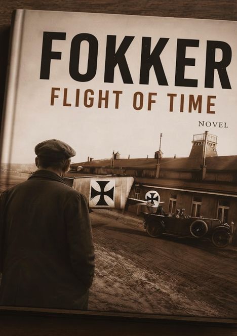 "FOKKER FLIGHT OF TIME NOVEL". Ein Mann blickt auf ein historisches Gebäude mit Flugzeugteilen und einem Auto.