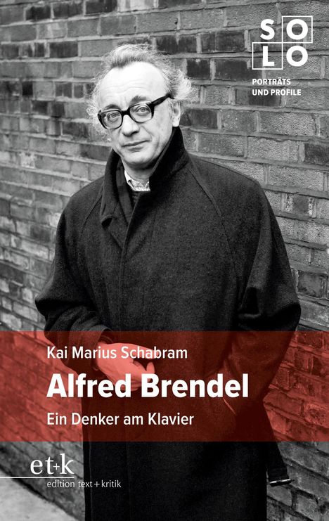 Kai Marius Schabram, Alfred Brendel, Ein Denker am Klavier. Schwarz-weißes Porträt eines Mannes in Mantel vor Ziegelwand.