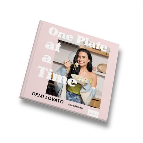 „One Plate at a Time“, „DEMI LOVATO“, „Koch dich frei“. Eine lächelnde Person hält einen Teller mit Essen.