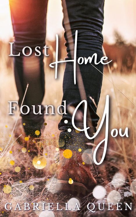 "Lost Home Found You" von GABRIELLA QUEEN. Füße in Stiefeln auf Feldweg, warme Farbtöne, helle Lichtpunkte.