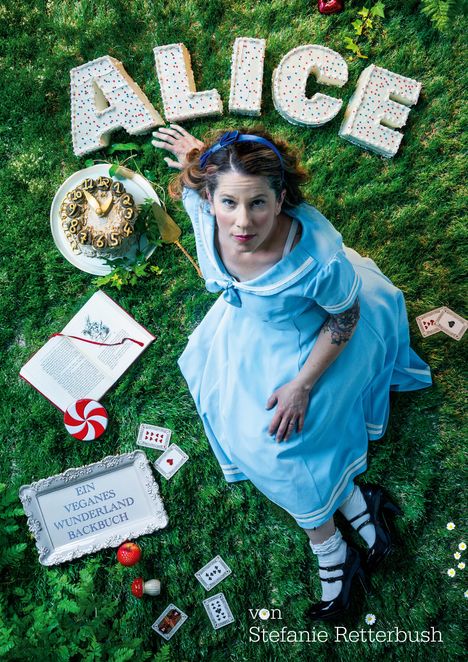 "ALICE" aus Kuchenbuchstaben, Schachbrett, Frau im blauen Kleid auf Gras mit Karten, Uhrkuchen, Buch und Früchten.