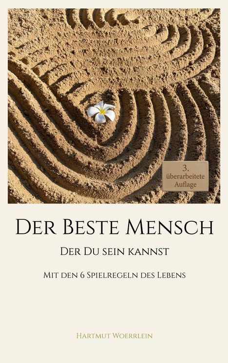 Buchtitel: "Der Beste Mensch" von Hartmut Woerrlein. Sandmuster mit einer weißen Blume. 3. überarbeitete Auflage.