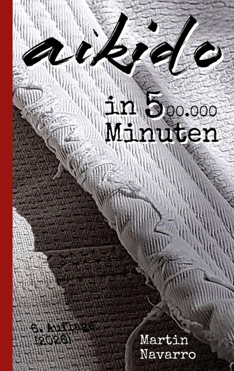 Text: "aikido in 5 Minuten, 6. Auflage (2026), Martin Navarro." Ein gefaltetes, texturiertes Tuch und ein roter Streifen links.