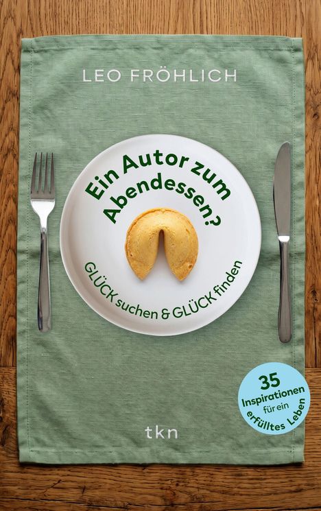 „Ein Autor zum Abendessen? GLÜCK suchen & GLÜCK finden“ auf einem Teller mit Glückskeks. Beigefarbene Tischdecke.