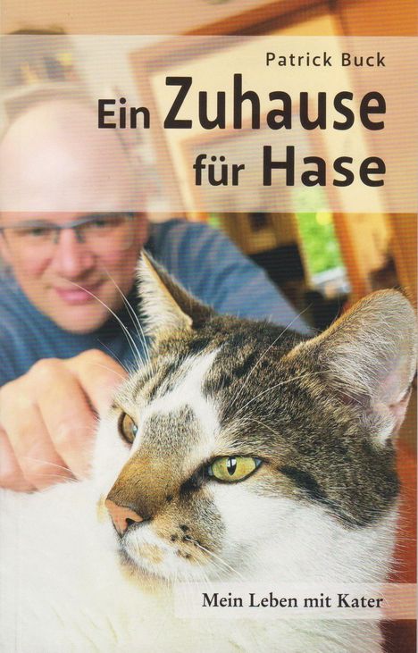 "Ein Zuhause für Hase" von Patrick Buck. Vordergrund: Eine Katze entspannt, im Hintergrund ein Mann mit Brille.