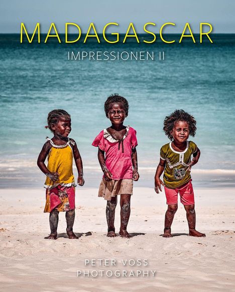MADAGASCAR IMPRESSIONEN II. Drei fröhliche Kinder am Strand vor dem Meer, barfuß in bunter Kleidung.