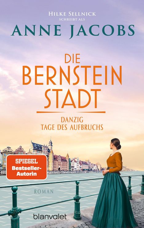 „Die Bernstein Stadt“ von Anne Jacobs. Frau in historischem Kleid blickt auf farbenfrohe städtische Uferpromenade.