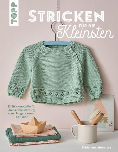 "Stricken für die Kleinsten" in großen Lettern. Ein mintgrüner Baby-Pullover auf einem Bügel, darunter Dekosachen.