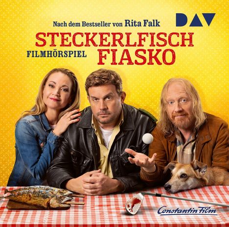 "Nach dem Bestseller von Rita Falk. Steckerlfisch Fiasko. Drei Personen und ein Hund an einem rot-weißen Tisch."