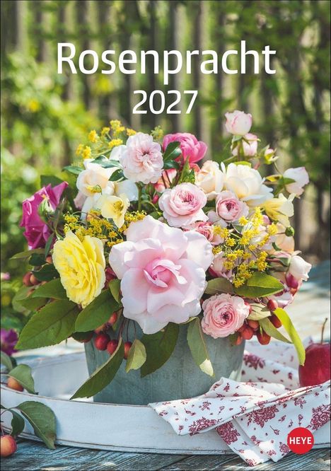 „Rosenpracht 2027“ zeigt bunte Rosen in einem Eimer auf einem Tisch, umgeben von grünen Blättern und roten Früchten.