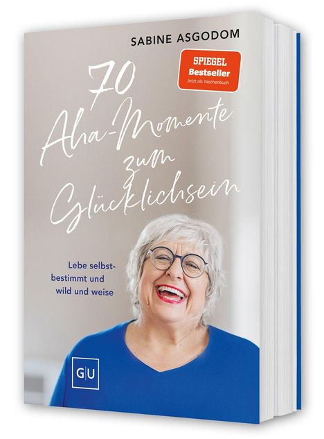 "70 Aha-Momente zum Glücklichsein. Lebe selbstbestimmt und wild und weise." Lachende Frau in blauem Oberteil.
