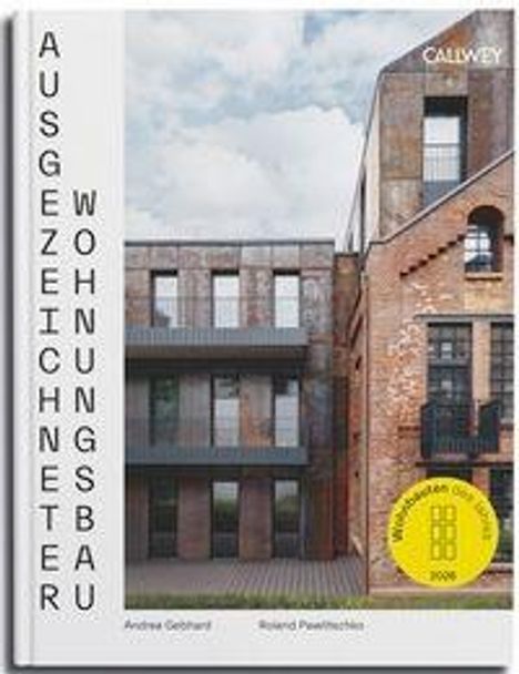 „AUSGEZEICHNETER WOHNUNGSBAU“ steht senkrecht. Modernes Gebäude aus Backstein und Metallpaneelen.