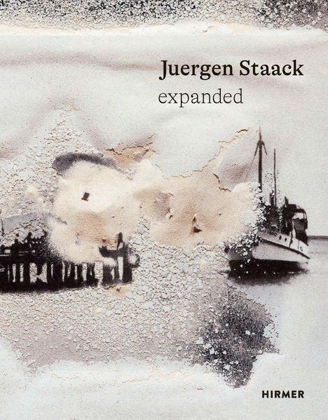 Text: "Juergen Staack expanded". Sandartige, abstrakte Wolken über einem unscharfen Stadthorizont mit Schiff.
