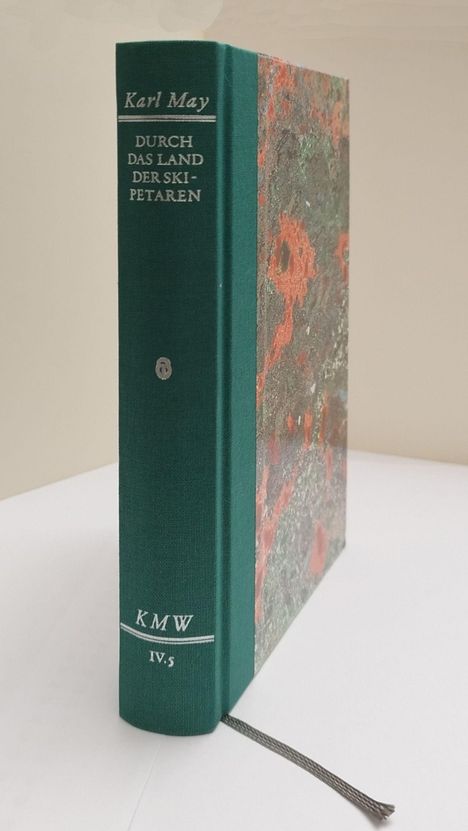 "Buchtitel: 'Durch das Land der Skipetaren' von Karl May. Grüner Buchrücken, bunte Seitenverzierung, silbernes Lesebändchen."