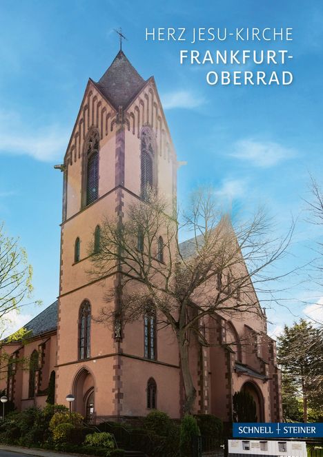 HERZ JESU-KIRCHE FRANKFURT-OBERRAD. Eine hohe, gotische Kirche vor klarem, blauem Himmel mit Bäumen im Vordergrund.