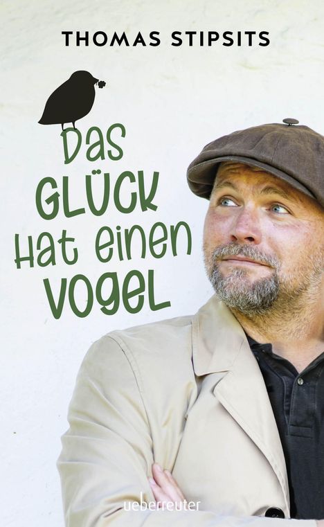 "Das Glück hat einen Vogel" von Thomas Stipsits. Ein Mann mit Schiebermütze schaut nachdenklich nach oben.