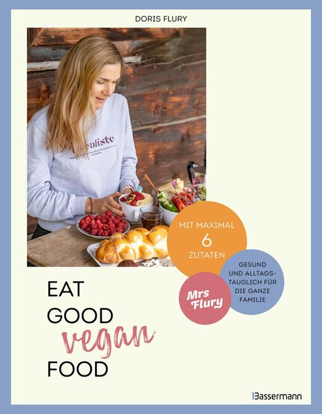 "DORIS FLURY. Eat Good Vegan Food. Mit maximal 6 Zutaten. Gesund und alltagstauglich für die ganze Familie." Eine Frau mit langen Haaren bereitet Essen an einem Tisch mit frischen Zutaten.