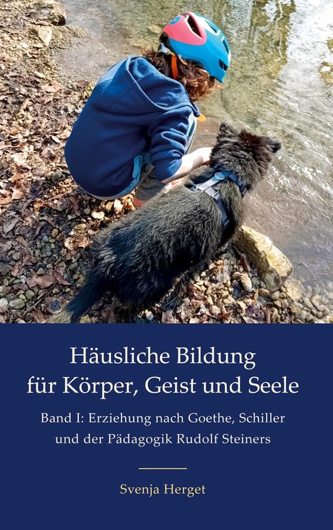 Ein Kind mit Helm kniet am Ufer eines Baches neben einem Hund.