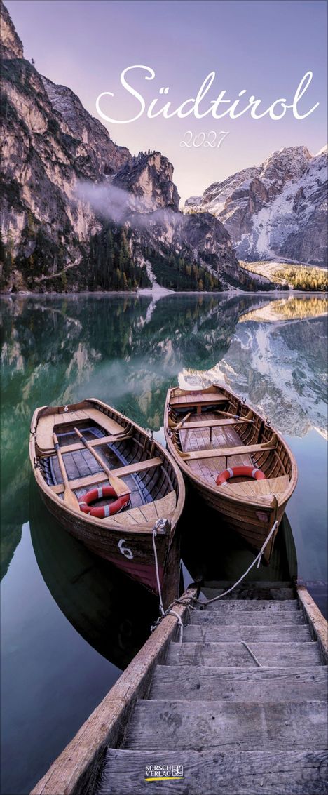 Südtirol 2024. Zwei Holzboote sind an einem Steg, umgeben von Bergen und einem ruhigen See mit klarem Wasser.
