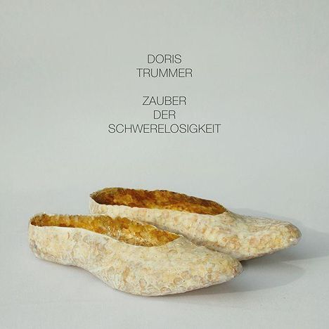 Text: "DORIS TRUMMER ZAUBER DER SCHWERELOSIGKEIT." Zwei helle, kunstvoll gestaltete Schuhe mit Textur.