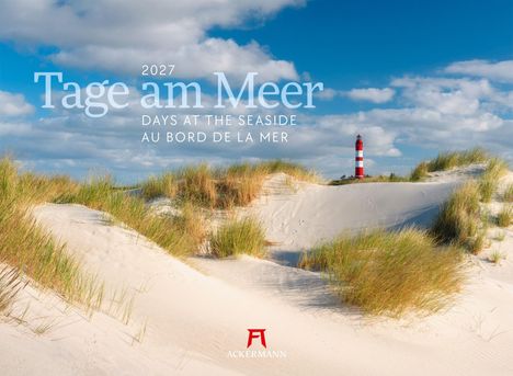 2027 Tage am Meer. Dünen mit hohem Gras, ein roter Leuchtturm am Horizont, blauer Himmel mit Wolken.