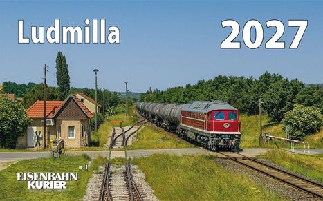 "Ludmilla 2027" in großen Buchstaben. Eine rote Lokomotive fährt mit Waggons durch eine grüne ländliche Gegend.
