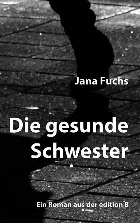 „Die gesunde Schwester“ von Jana Fuchs, darunter „Ein Roman aus der edition 8“. Schatten von Füßen auf Pflastersteinen.