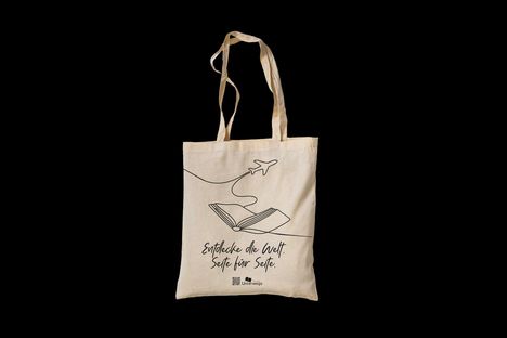"Entdecke die Welt. Seite für Seite." Einfache Linie zeigt Flugzeug und Buch auf Stofftasche.