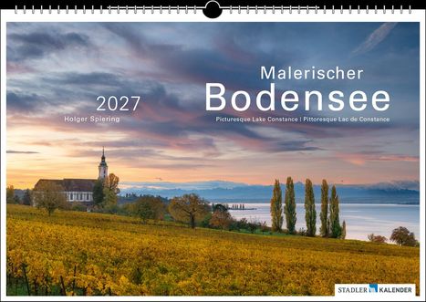 „Malerischer Bodensee“, „2027“, „Holger Spiering“. Abendlandschaft mit Kirche, Weinreben und See in der Ferne.