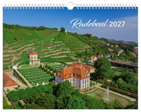 Radebeul 2027. Blick auf Weinberge und ein Herrenhaus mit Garten, umgeben von üppiger Vegetation und einem Brunnen.