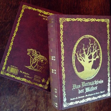 „Das Vermächtnis der Wälder“ in goldener Schrift auf braunem Buch. Ein Baumemblem auf dem Umschlag. Links ein Bär.