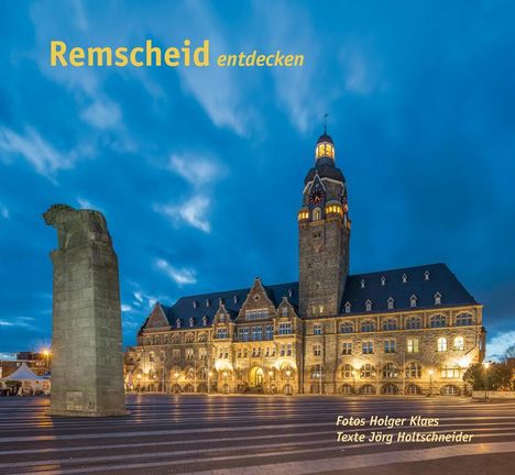 „Remscheid entdecken“ steht in gelber Schrift. gezeigt wird ein beleuchtetes historisches Gebäude bei Dämmerung.