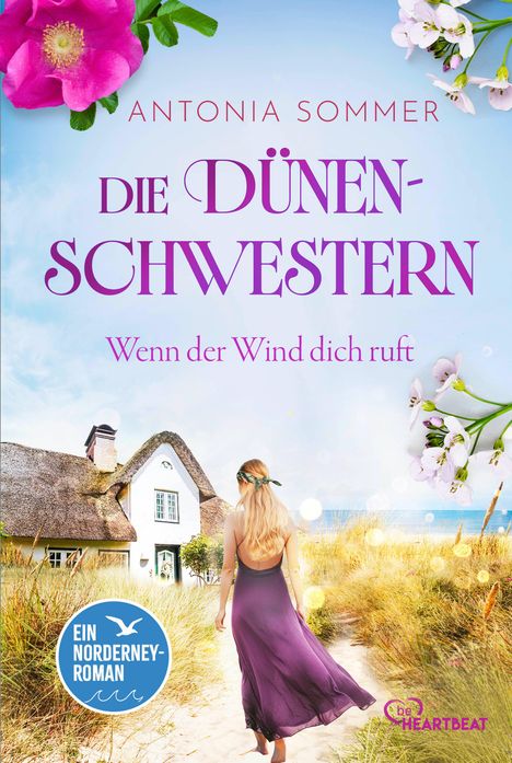 "Die Dünenschwestern. Wenn der Wind dich ruft. Ein Norderney-Roman. BeHEARTBEAT. Blume, Haus, Frau in lila Kleid am Strand."