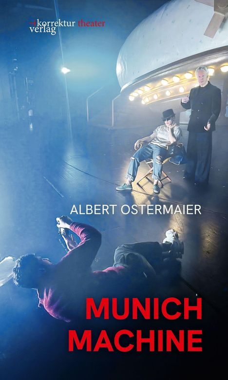 ALBERT OSTERMAIER, MUNICH MACHINE. Eine Bühne mit zwei Personen, eine sitzend, die andere stehend, im Rampenlicht.