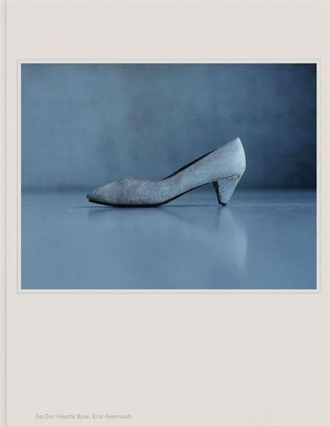 "As Our Hearts Bow, Eric Asamoah." Ein eleganter Damenschuh mit kleinem Absatz, auf einem glatten, graublauen Hintergrund.