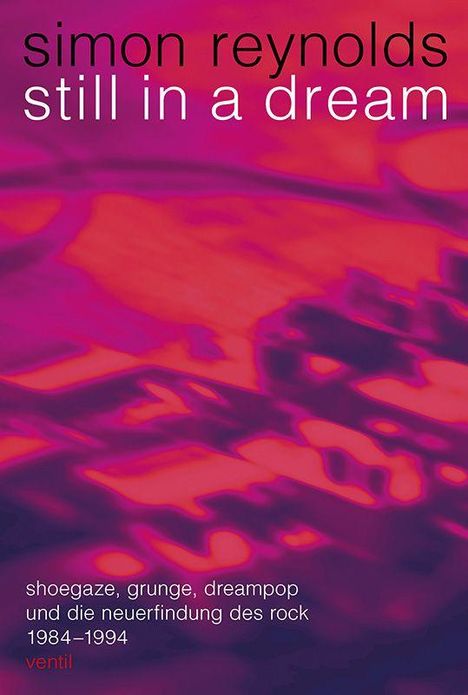 Text: "simon reynolds still in a dream. shoegaze, grunge, dreampop und die neuerfindung des rock 1984–1994 ventil". Hintergrund: Abstrakte, verschwommene rosa- und lila-Töne.