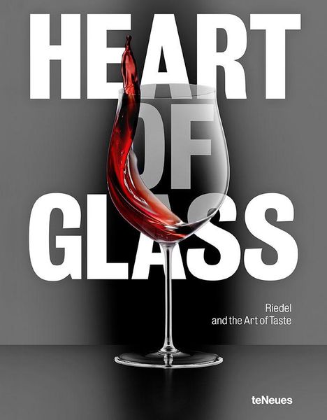 "HEART OF GLASS" in großen weißen Buchstaben. Ein Weinglas mit roter Flüssigkeit in dynamischer Bewegung.