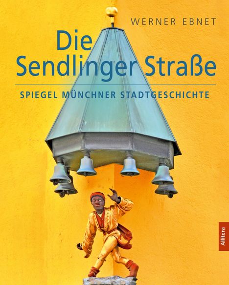 "Die Sendlinger Straße. Spiegel Münchner Stadtgeschichte. Werner Ebnet." Statue unter Glocke vor gelber Wand.