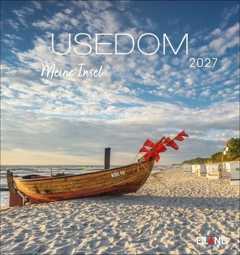 USEDOM, Meine Insel 2027. Ein Holzboot mit roten Fahnen am Sandstrand vor blauem Himmel mit Wolken.