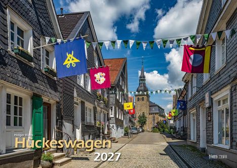 Text: "Holger Klaes, Hückeswagen, 2027". Kopfsteinpflasterstraße mit Fachwerkhäusern und bunten Wimpeln; Kirchturm im Hintergrund.