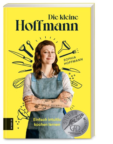 "Die kleine Hoffmann", "SOPHIA HOFFMANN", "Einfach intuitiv kochen lernen". Frau mit Tattoos und Schürze, umgeben von Küchenutensilien.