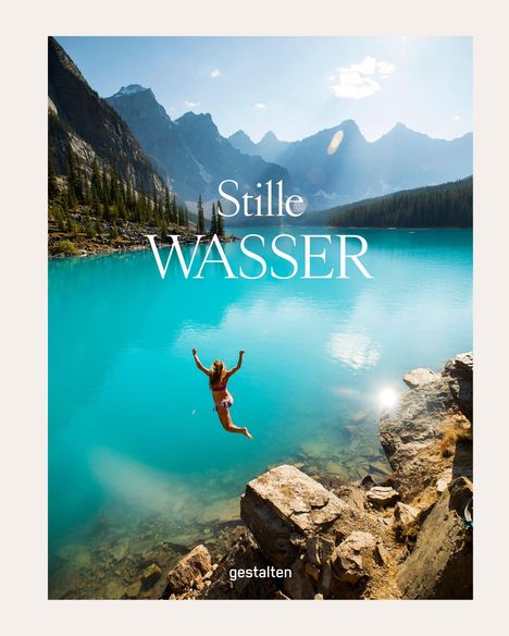 Text: "Stille WASSER", "gestalten". Eine Person springt von Felsen in einen klaren, türkisfarbenen See, umgeben von Bergen.