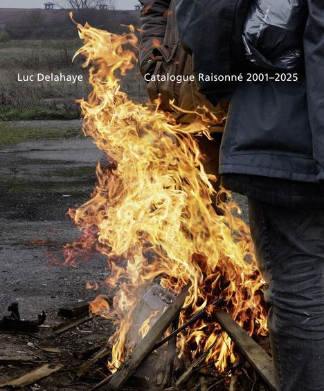 Text: "Luc Delahaye Catalogue Raisonné 2001–2025". Ein Lagerfeuer brennt auf einem verlassenen Gelände, mit Personen im Hintergrund.