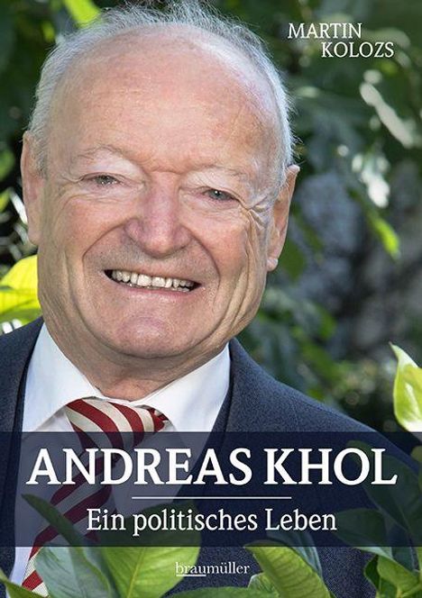 "ANDREAS KHOL - Ein politisches Leben" von Martin Kolozs. Ein lächelnder älterer Mann im Anzug vor grünen Blättern.