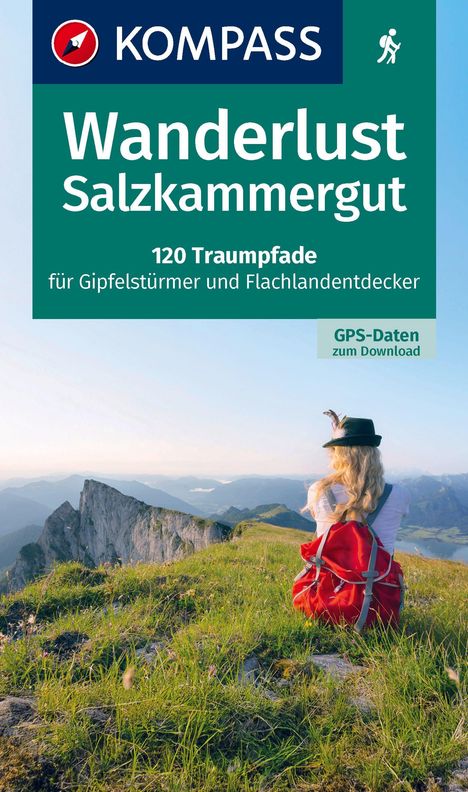 Logo "KOMPASS". Text: "Wanderlust Salzkammergut. 120 Traumpfade für Gipfelstürmer und Flachlandentdecker. GPS-Daten zum Download." Frau mit rotem Rucksack sitzt auf Wiese mit Bergblick.