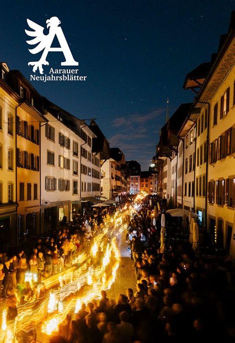 Text: "Aarauer Neujahrsblätter." Ein belebter Straßenumzug bei Nacht mit Lichtern und vielen Menschen, umgeben von Häusern.