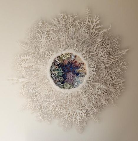 Ausschnitt eines filigranen weißen Papiers mit einem bunten Zentrum aus Korallenmustern.