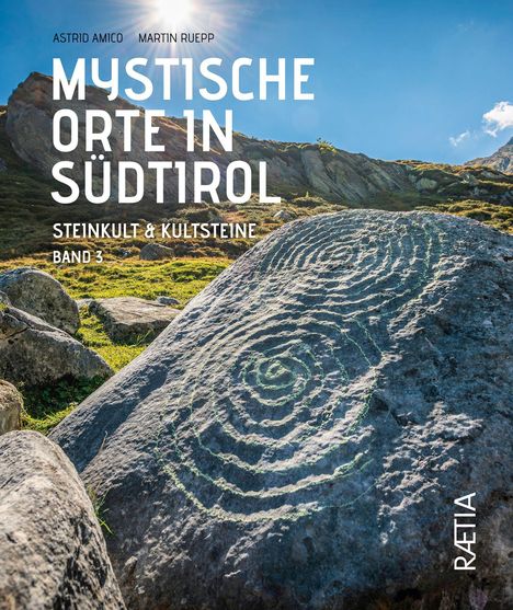 Titel: Mystische Orte in Südtirol. Vorne: Fels mit kreisförmigen Gravuren. Hintergrund: Berge und blauer Himmel.