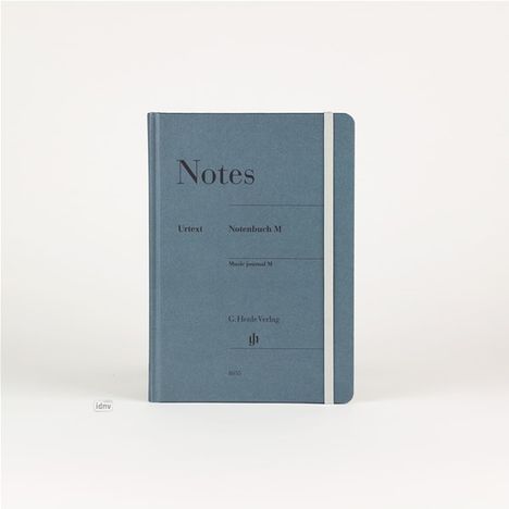 Auf einem blaugrauen Notizbuch steht: "Notes, Urtext, Notenbuch M, Music journal M, C. Henle Verlag". Weiße Gummibandbindung.