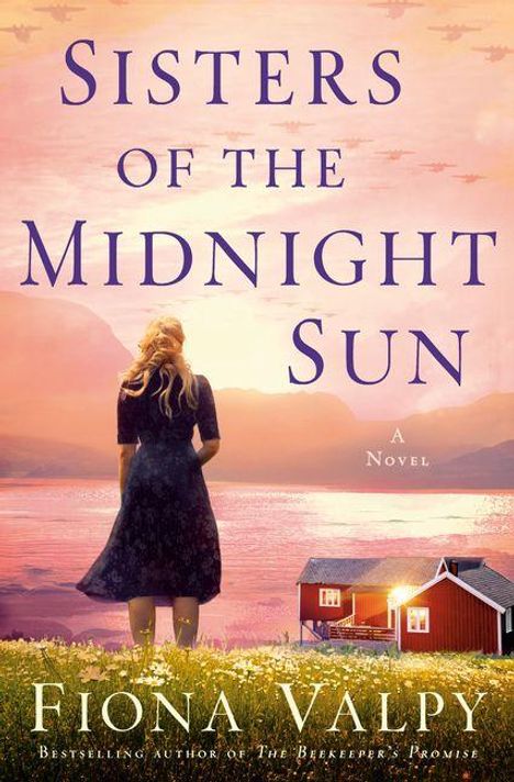 "Sisters of the Midnight Sun", Fiona Valpy. Eine Frau steht vor Wasser, mit Hütten und Bergen im Hintergrund bei Sonnenuntergang.